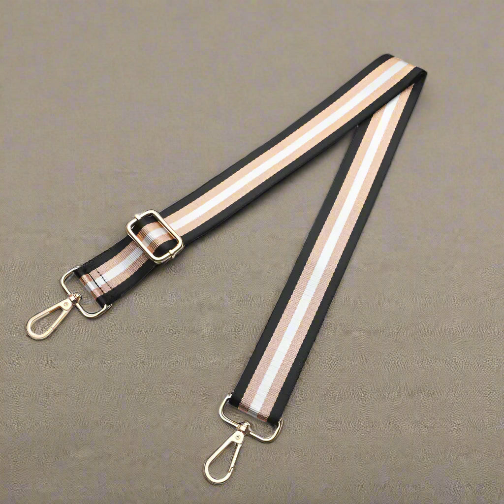 Striped bag strap with gold hardware on a white surface