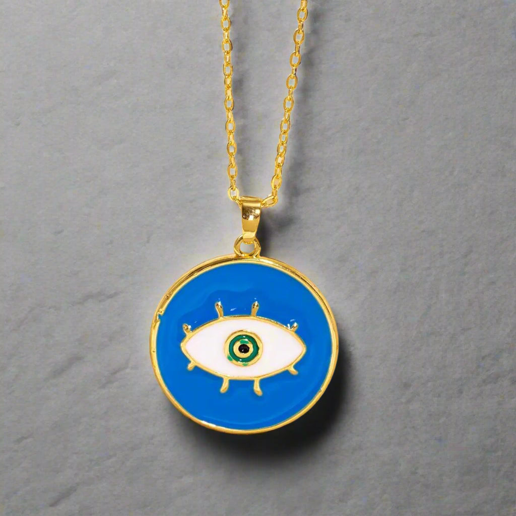 Gold necklace with a blue evil eye pendant on a beige background